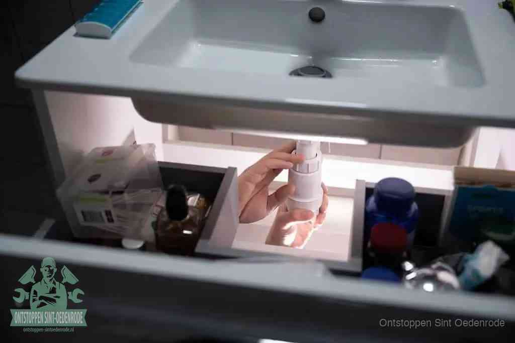 Een pompfles met zeep boven een wastafel, de heet water en afwasmiddel-methode om een vetprop in de afvoer los te maken in Sint Oedenrode