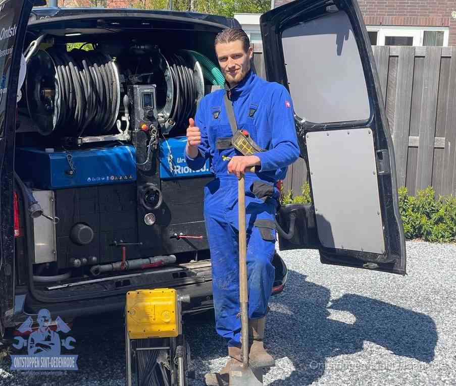 Een monteur bij de werkbus met grote hogedruk-slanghaspels, apparatuur voor hardnekkige afvoerverstoppingen in Sint Oedenrode