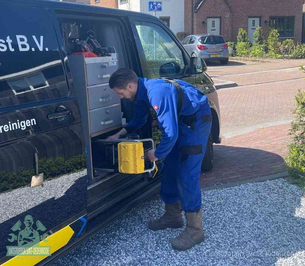 Een monteur pakt buiten op de oprit gereedschap uit de bedrijfsbus, het moment om een professional in te schakelen voor een verstopte afvoer in Sint Oedenrode
