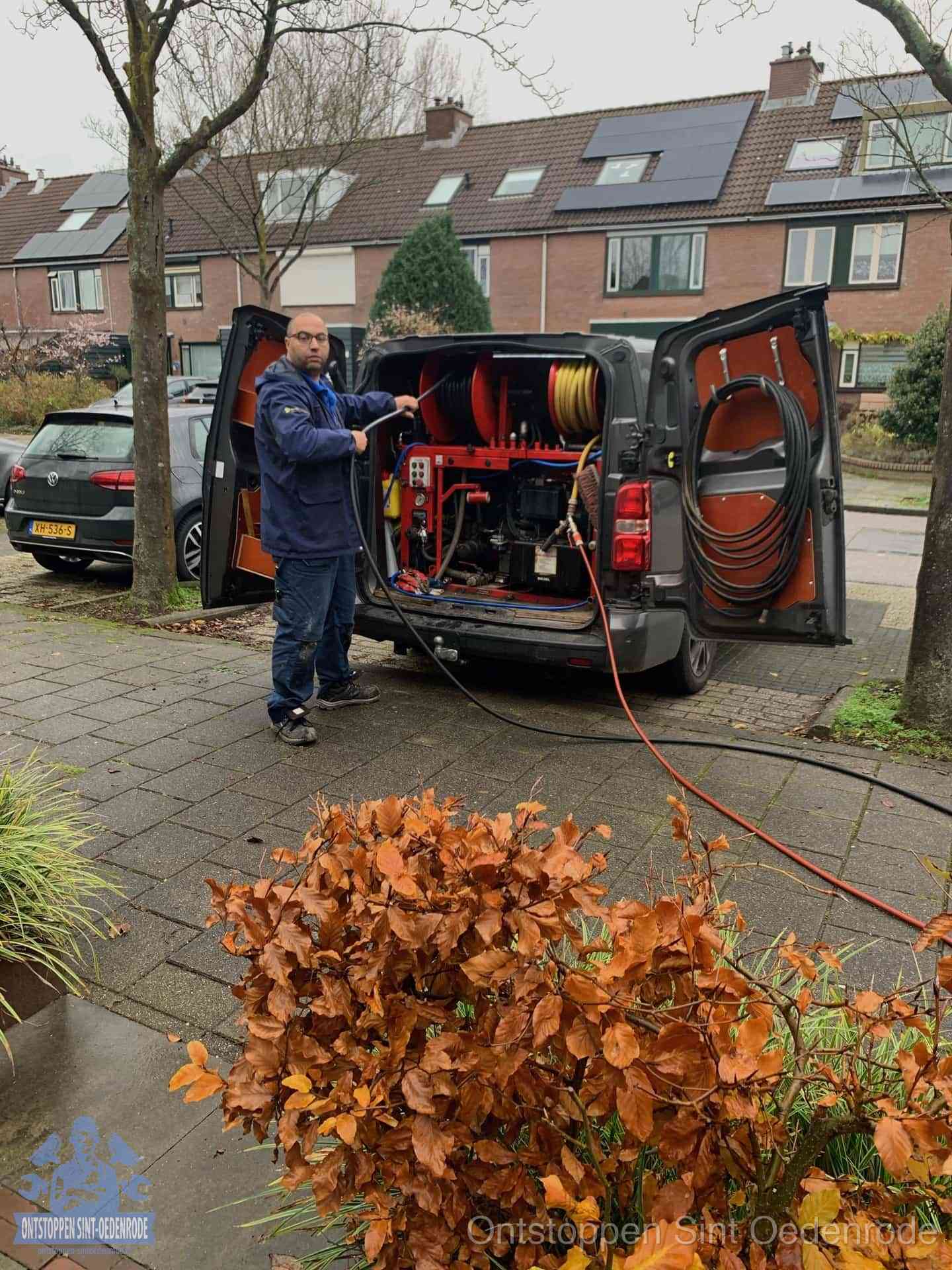 Rioolservice in de wijk in Sint Oedenrode Monteur met rioolreinigingsbus levert rioolservice in de wijk in Sint Oedenrode