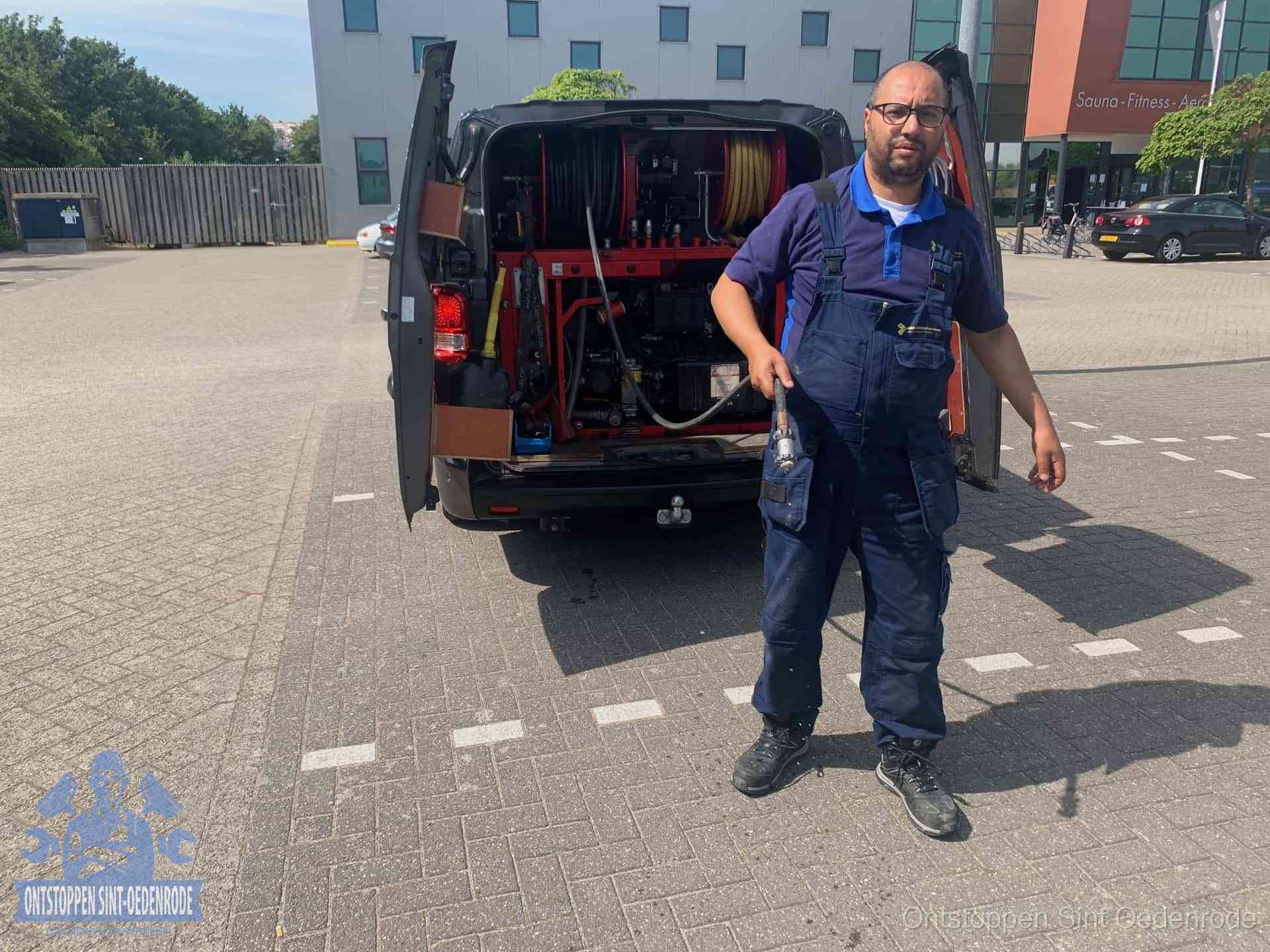 Een monteur bij zijn bestelbus met een hogedruk- en rioolreinigingsunit, klaar om de oorzaak van terugkerende wc-verstoppingen aan te pakken in Sint Oedenrode