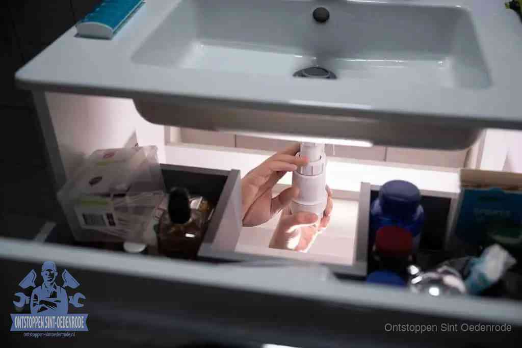 Een pompfles met zeep boven een wastafel in de toiletruimte, de warm water en afwasmiddel-methode om de wc te ontstoppen in Sint Oedenrode